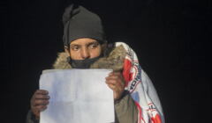 Okutana osoba z kartką z napisem po angielsku „Chcę azylu w Polsce