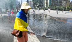 Kobieta flagą Ukrainy chłodzi się przy kurtynie wodnej
