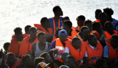 Ciemnoskórzy ludzie w kamizelkach ratunkowych na łodzi