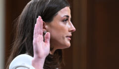 Młoda kobieta z profilu, podnosi rękę w geście przysięgi