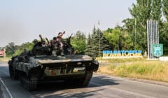 Ukrainian soldiers on the top of a Ukrainian armoured fighting vehicle gesture as they drive down at the exit of Kramatorsk, eastern Ukraine, on July 6, 2022, amid the Russian invasion of Ukraine. (