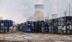 Rzędy zbiorników z odpadami, w tle kominy elektrowni