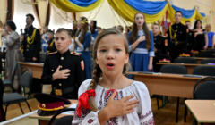 Dziewczynka z ręką na sercu śpiewa hymn w ukraińskiej szkole