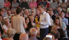 Donald Tusk podczas spotkania z wyborcami stoi z mikrofonem wśród ludzi
