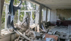 Wnętrze sali w zbombardowanym budynku szkoły, wielka dziura w ścianie z oknami