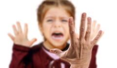 Zapłakane dziecko, na pierwszym planie ręka podniesiona do klapsa